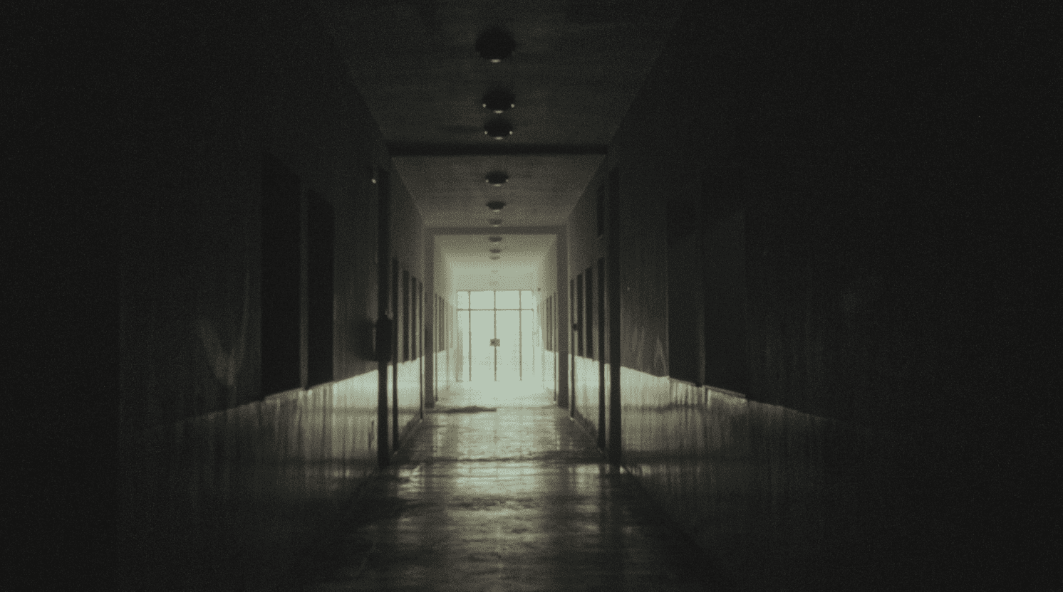 Dimly lit hallway with shadows, evoking the unsettling feeling of being watched