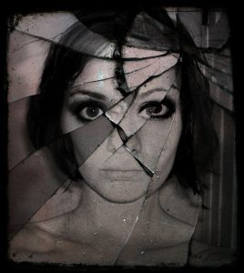 black and white image of woman behind broken glass