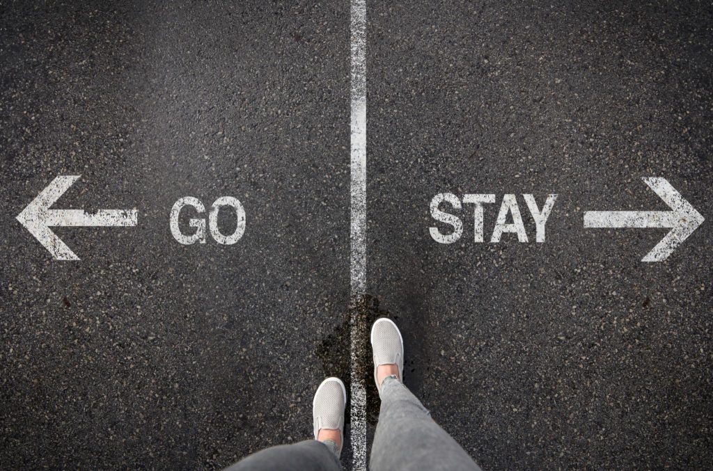 person standing at go or stay sign representing the difference between healing and avoiding