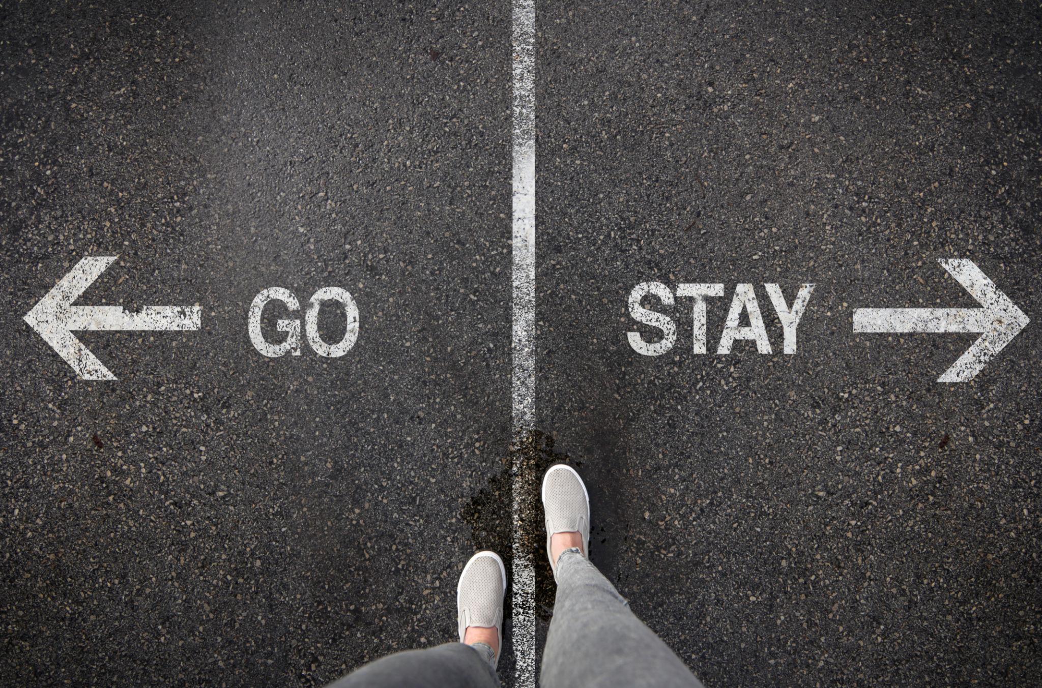 person standing at go or stay sign representing the difference between healing and avoiding